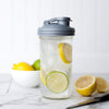 Clear mason jar filled with iced water and slices of lemon and lime, topped with a gray reusable lid featuring a pour spout and carry loop, suited for Home & Decor and Household Helpers collections.