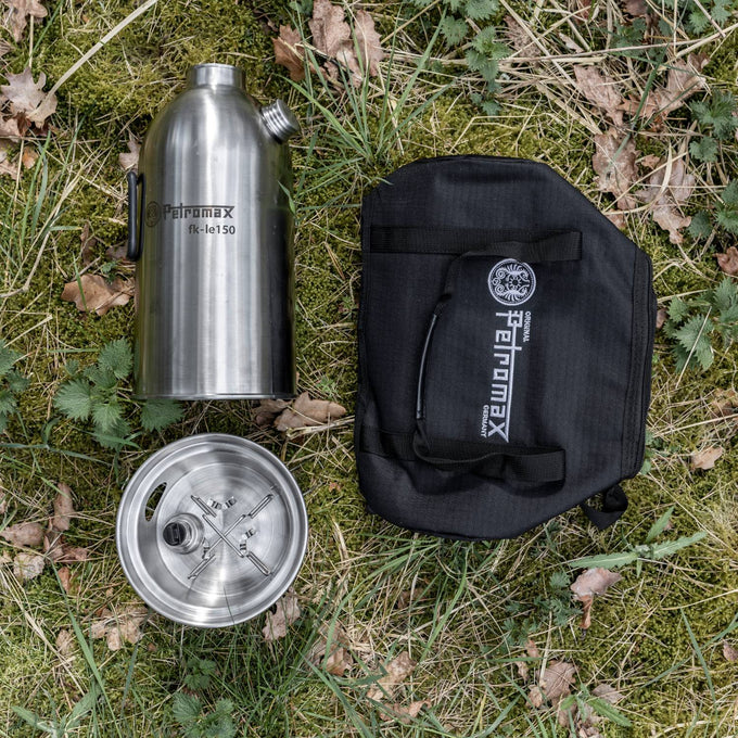 Overhead view of a portable stainless steel fire kettle with screw-on spout and black carry bag, laid on grass, suitable for Camping, Emergency Supplies, Farm, Garden & Tool, and Best Sellers collections.
