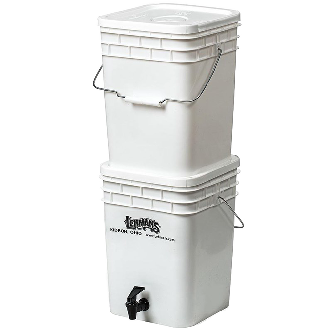 White two-bucket water filtration system with metal handles and a spigot on the lower bucket, designed for durable, portable water purification in farm, garden, emergency, and appliance use.