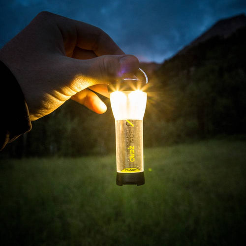Hand holding a compact rechargeable flashlight and lantern emitting bright light outdoors at dusk, highlighted for use in lamps & lighting, emergency supplies, and battery collections.