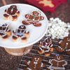 Assorted gingerbread cookies decorated with colorful icing and candies cooling on a wire rack and displayed on a white stand, perfect for Kitchen & Food, Cookware, and Baking Supplies collections.