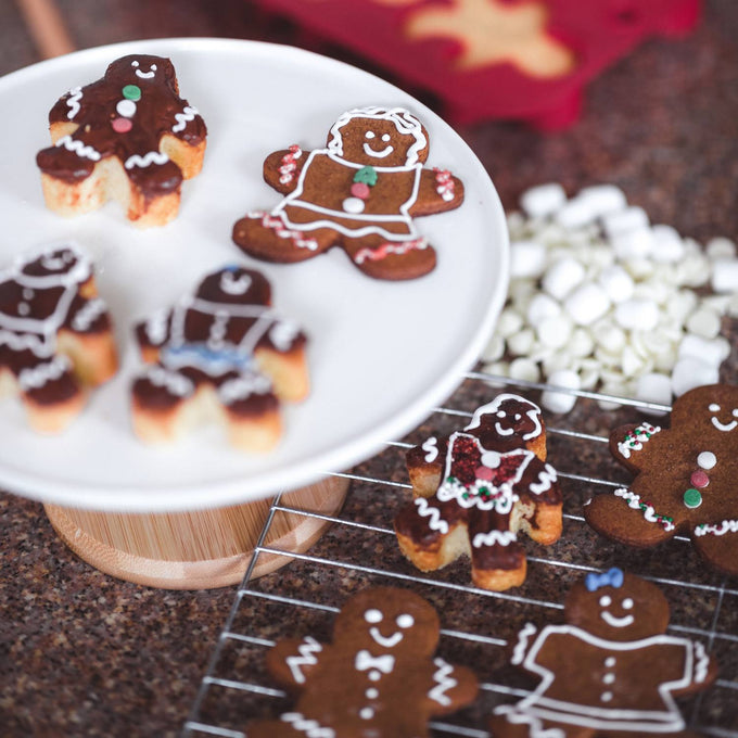 Assorted gingerbread cookies decorated with colorful icing and candies cooling on a wire rack and displayed on a white stand, perfect for Kitchen & Food, Cookware, and Baking Supplies collections.