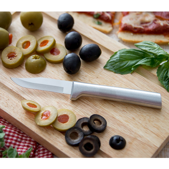 Sleek paring knife with a satin-finished cast aluminum handle and sharp carbon stainless steel blade resting on a wooden board with sliced olives, fresh basil, and pizza, ideal for kitchen and food prep in USA made collections.