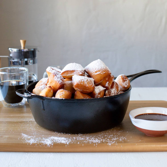 Handcrafted Lodge Blacklock cast iron deep skillet filled with golden, powdered sugar-dusted beignets, accompanied by coffee and chocolate sauce, featured in Kitchen & Food, Cookware, Cast Iron, USA Made, Best Sellers, and Promo Eligible collections.