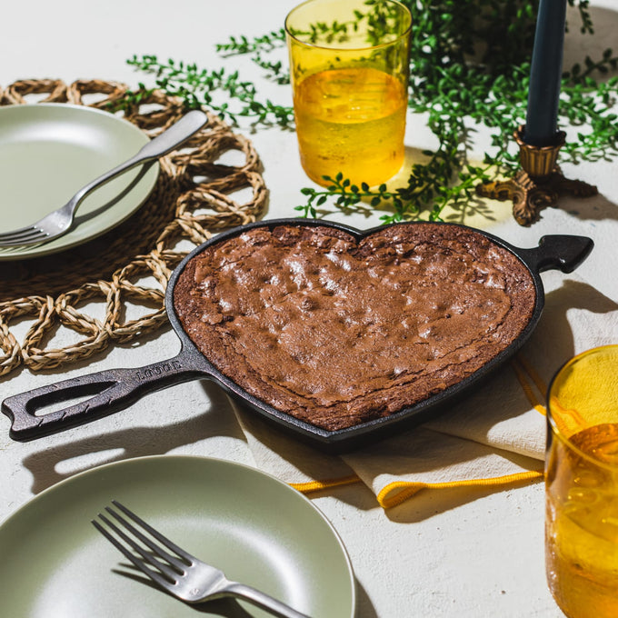 Handcrafted cast iron heart-shaped skillet with arrow handle, made in USA, shown with freshly baked heart-shaped dessert, ideal for Kitchen & Food, Cookware, Cast Iron, Baking Supplies, USA Made, Best Sellers, and Promo Eligible collections.