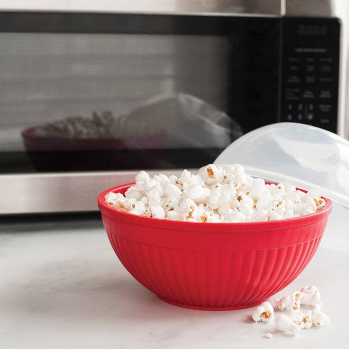 Red BPA-free microwavable bowl filled with freshly popped popcorn, shown with a clear vented lid and stainless steel microwave in the background, ideal for Kitchen & Food, Popcorn, and USA Made collections.