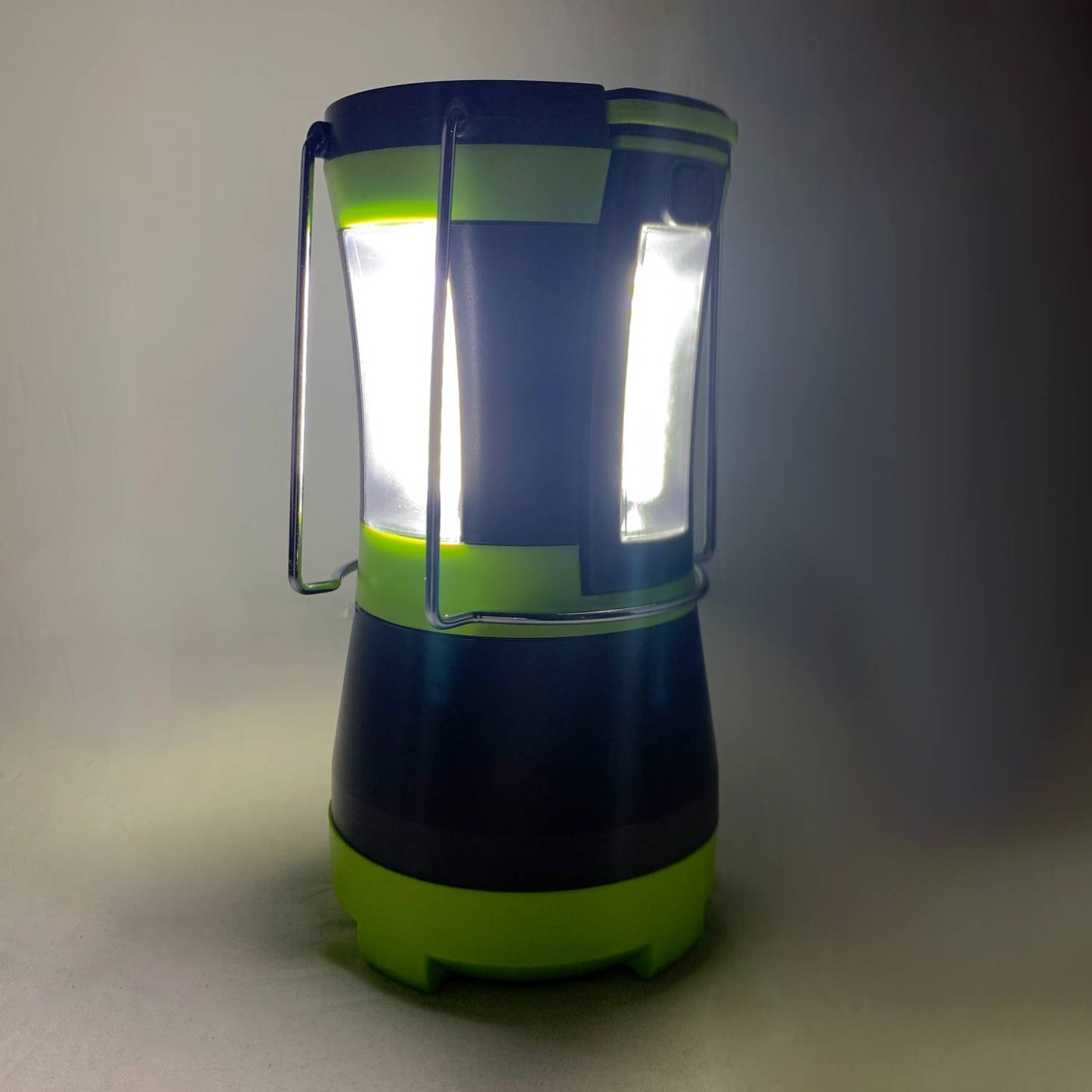 Bright LED camping lantern with sturdy metal handles and green accents, providing powerful white light for use in emergency supplies, outdoor, and battery-powered lighting collections.