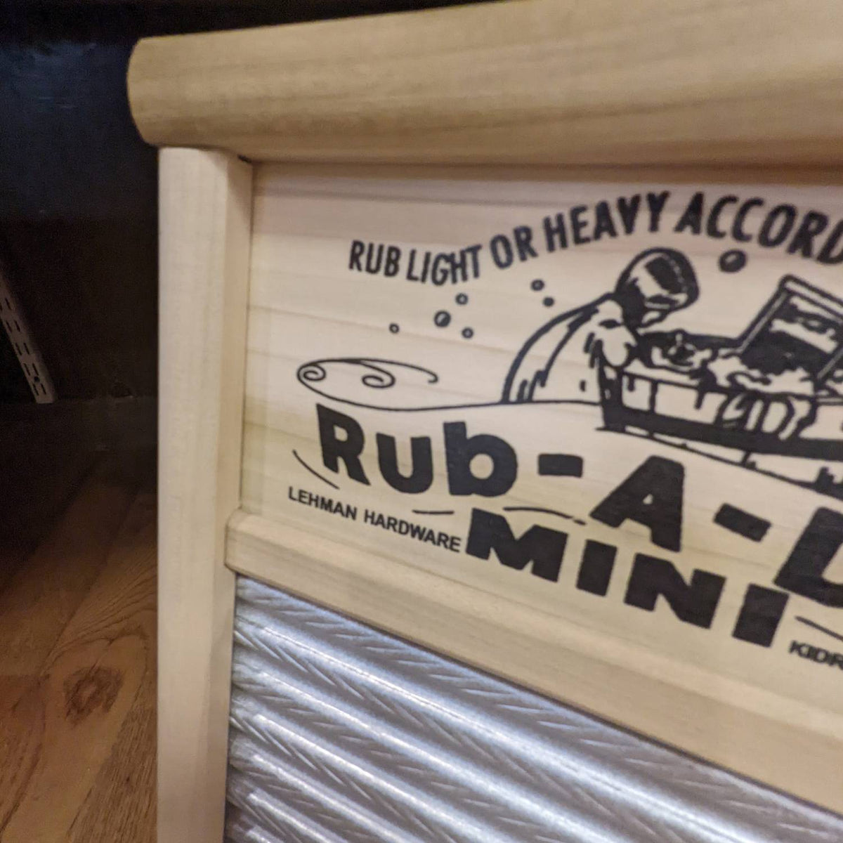 Close-up of handcrafted Lehman's mini tin spiral washboard showing smooth wooden frame and decorative printed nameplate, featured in USA Made, Laundry Supplies, and Home & Decor collections.