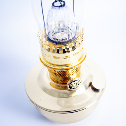 Polished brass oil lamp with a clear glass chimney and fine mesh mantle, handcrafted for use in farm, garden, emergency, and table lamp collections.