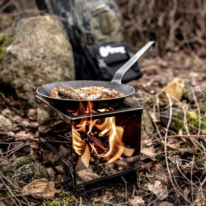 Handcrafted wrought iron pan cooking sausages over a wood fire in a compact outdoor stove, ideal for Farm, Garden & Tool, Kitchen & Food, Camping, Cookware, Pots and Pans, Best Sellers, and Promo Eligible collections.