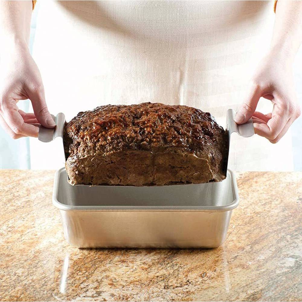 Hands lifting a cooked meatloaf with a perforated aluminum trivet from a matching loaf pan on a kitchen countertop, handcrafted and made in USA, featured in Kitchen & Food, Cookware, Baking Supplies, Pots and Pans, USA Made, Best Sellers, Promo Eligible collections.