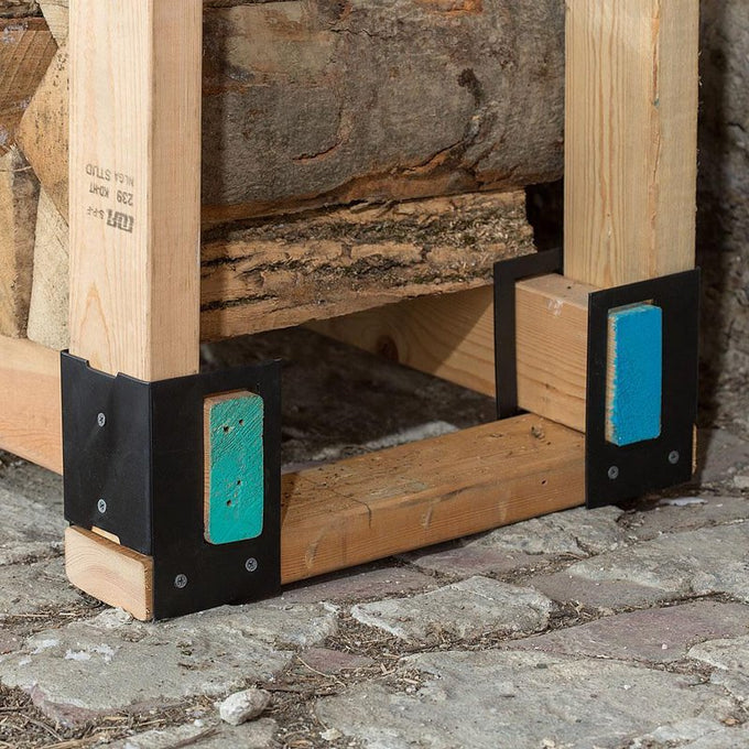 Close-up of sturdy steel log rack brackets securing wooden beams to keep firewood elevated and dry, ideal for farm, garden, and homesteading use in wood cutting and hauling tasks.