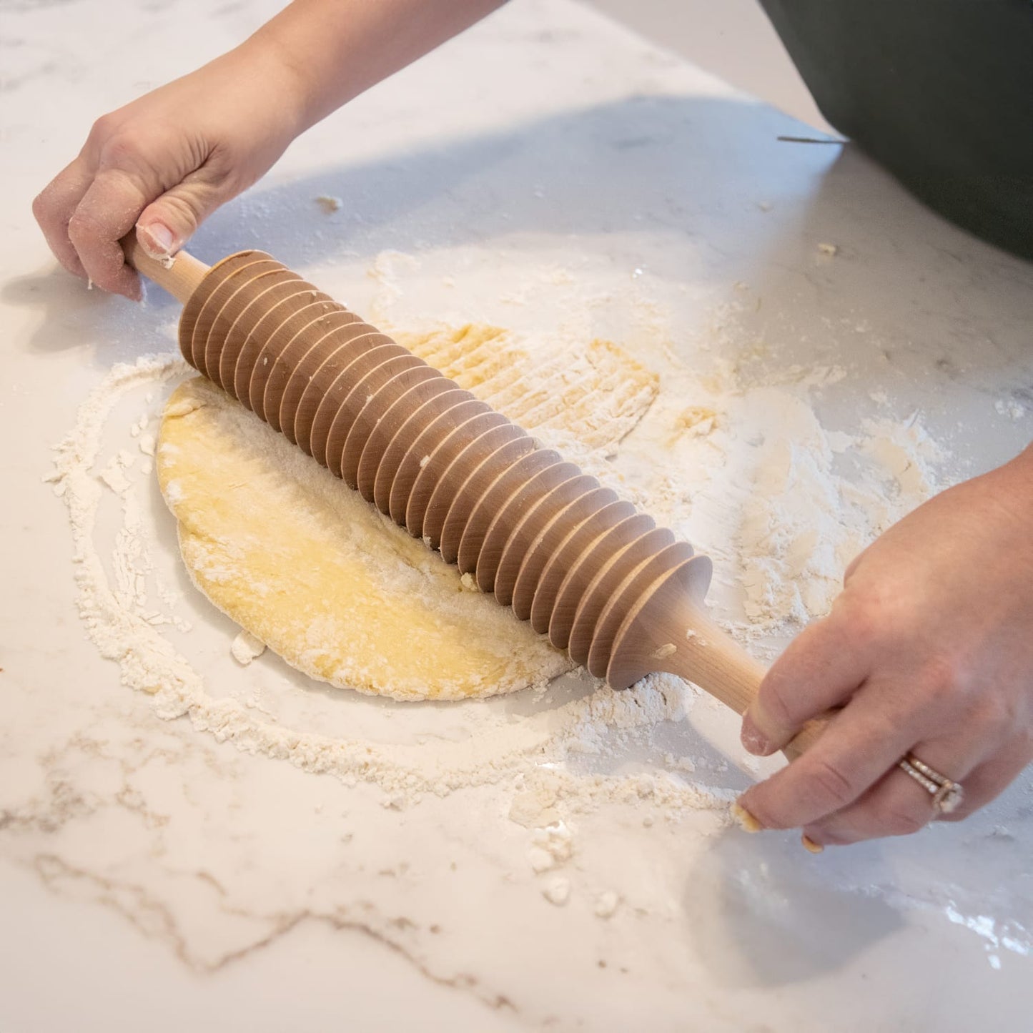 Hands using a handcrafted unfinished cherry wood noodle cutter to slice dough on a floured marble surface, highlighting Kitchen & Food, Food Prep, and Amish Made collections.