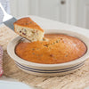 Handmade stoneware pie pan with double blue stripes holding a freshly baked golden brown cake, set on a woven placemat, ideal for Kitchen & Food, Baking Supplies, and USA Made collections.