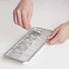 Hands lifting the handle of a handcrafted aluminum ice cube tray with removable divider, ideal for Farm, Garden & Tool, Kitchen & Food, Kitchen Gadgets, and Homesteading collections.