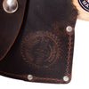 Close-up of a dark brown leather axe sheath with visible stitching, metal rivets, and an embossed circular logo, showcasing handcrafted Amish-made quality for outdoor and camping use.