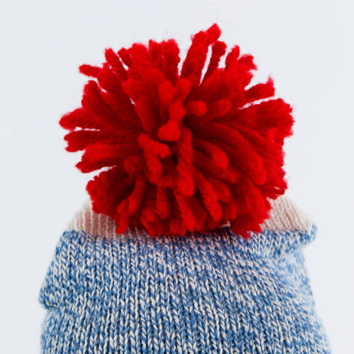 Close-up of a hand-stitched blue knit hat topped with a bright red yarn pom-pom, handcrafted in the USA, featured in Toys, Books & Games, USA Made, Children's Toys, Indoor Play, Best Sellers, and Promo Eligible collections.