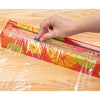 Hand sliding the cutter across a reusable dispenser of colorful plastic wrap with citrus design on wooden surface, ideal for Kitchen & Food and Storage and Serving collections.