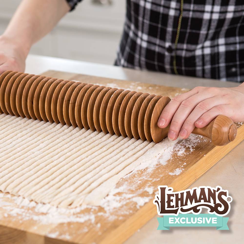 Handcrafted unfinished cherry wood noodle cutter with multiple evenly spaced wheels cutting 3/8-inch noodles on floured wooden board, fitting Kitchen & Food and Amish Made collections.