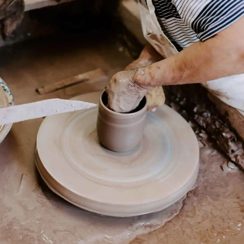 Artisan shaping wet clay on a pottery wheel, handcrafting a stoneware piece in a rustic workshop, highlighting handmade craftsmanship for Home & Decor and USA Made collections.