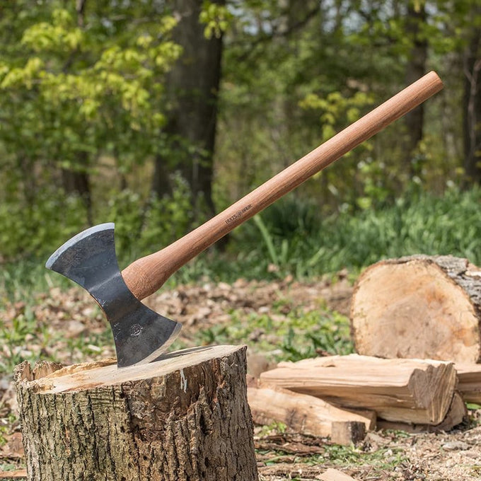 Handcrafted double-headed axe with Swedish steel blades and a smooth wooden handle embedded in a tree stump outdoors, suited for farm tools, wood cutting, and hardware collections.