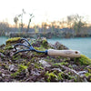 Handcrafted cultivator with three sturdy curved tines and a smooth wooden handle featuring a hanging hole, resting on mossy tree bark in an outdoor garden setting, ideal for Farm, Garden & Tool and Digging and Cultivating collections.
