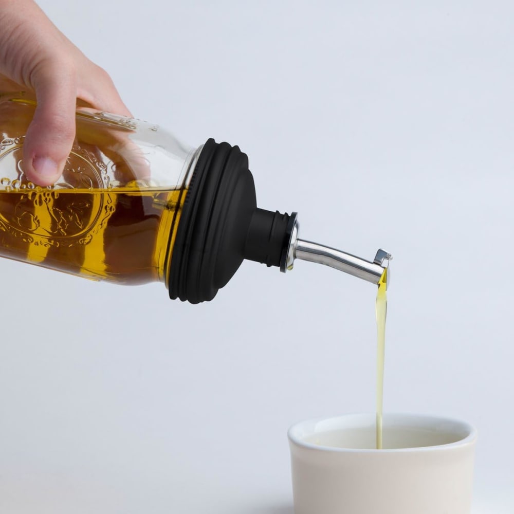 Black pour spout lid attached to a regular-mouth glass jar dispensing olive oil into a white ceramic bowl, part of Kitchen & Food, Kitchen Gadgets, USA Made, and Best Sellers collections.