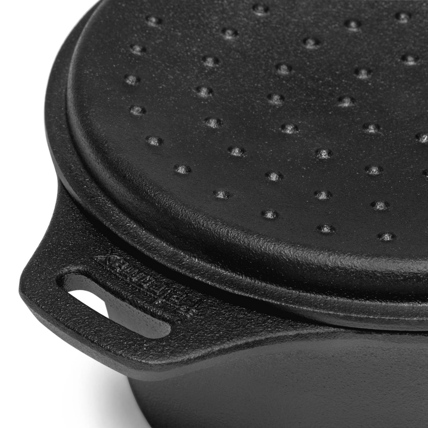 Close-up of a handcrafted heavy-duty cast iron saucepan with a self-basting lid featuring raised bumps, designed for outdoor cooking and ideal for farm, garden, and camping use.