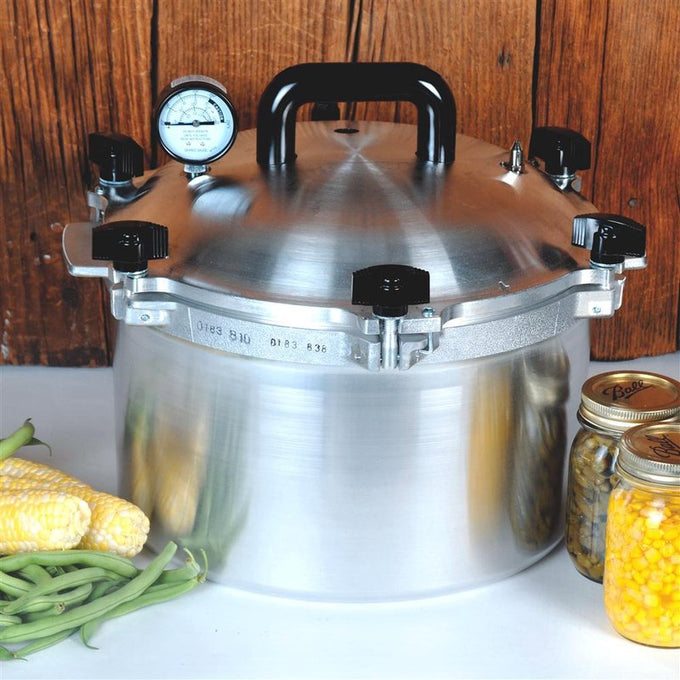 Heavy-duty polished aluminum pressure canner with black handles, pressure gauge, and secure locking lid, handcrafted in USA, perfect for food preservation and homesteading collections.