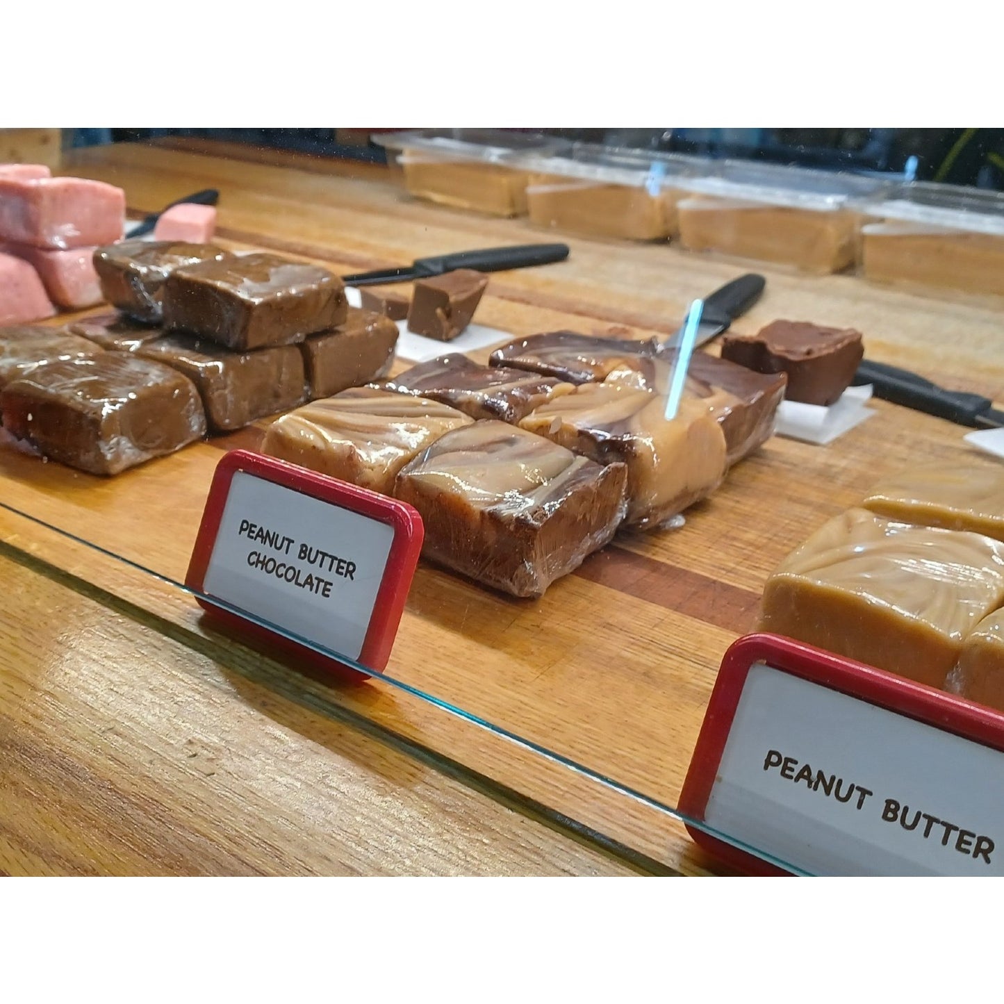 Assorted handcrafted creamy peanut butter and chocolate peanut butter fudge squares with smooth, rich textures displayed behind a glass counter, featured in Kitchen & Food, Food, Snacks and Sweets, USA Made, Best Sellers, and Promo Eligible collections.