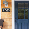 Handcrafted black and silver custom address plaque with bold white numbers mounted on natural wood siding next to a deep blue glass-paneled front door, made in USA for Home & Decor, Household Helpers, Mailboxes and Address Signs collections.