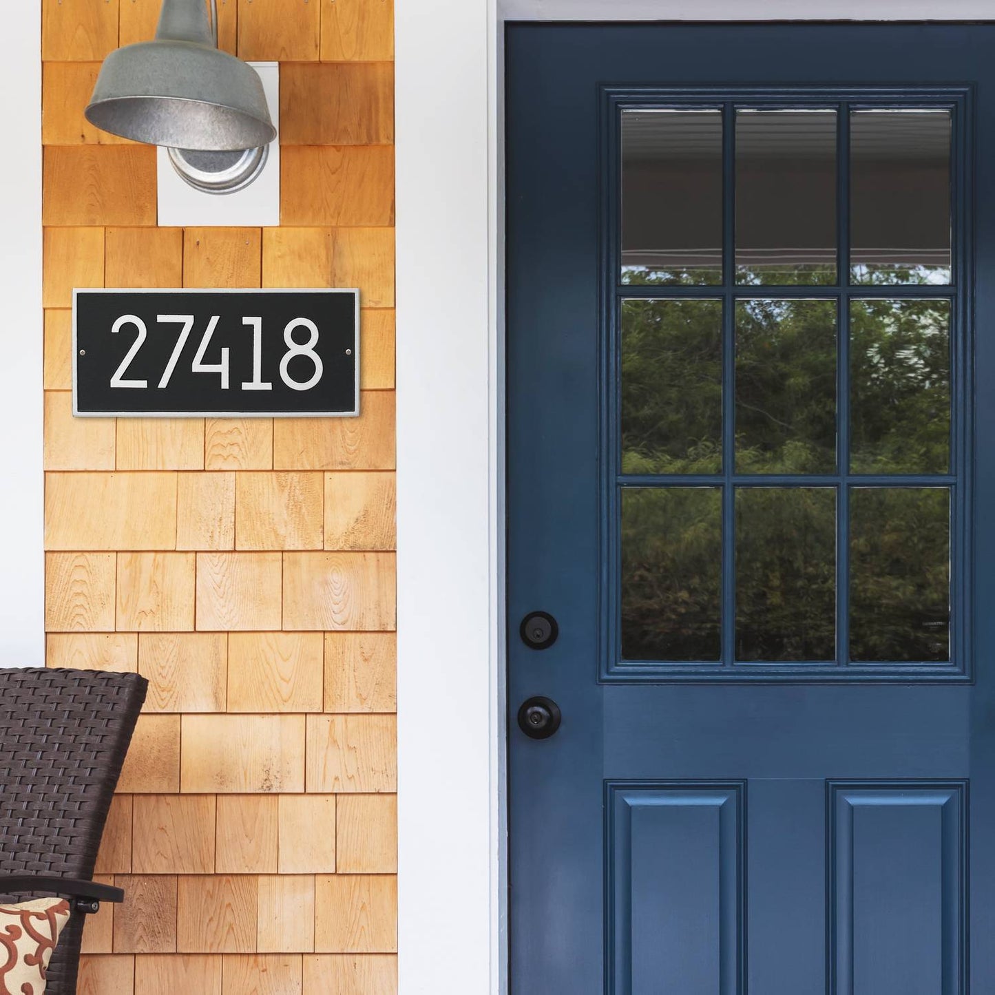 Handcrafted black and silver custom address plaque with bold white numbers mounted on natural wood siding next to a deep blue glass-paneled front door, made in USA for Home & Decor, Household Helpers, Mailboxes and Address Signs collections.