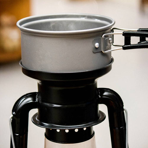 Close-up of a handcrafted black powder-coated steel lantern cooker with a metal pot simmering on top, perfect for camping, emergency supplies, and outdoor use collections.