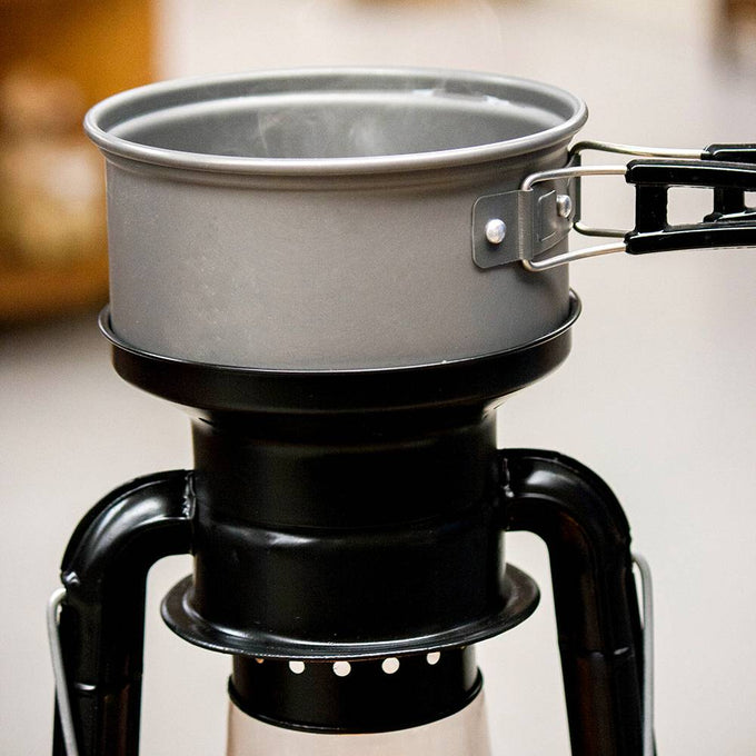 Close-up of a handcrafted black powder-coated steel lantern cooker with a metal pot simmering on top, perfect for camping, emergency supplies, and outdoor use collections.