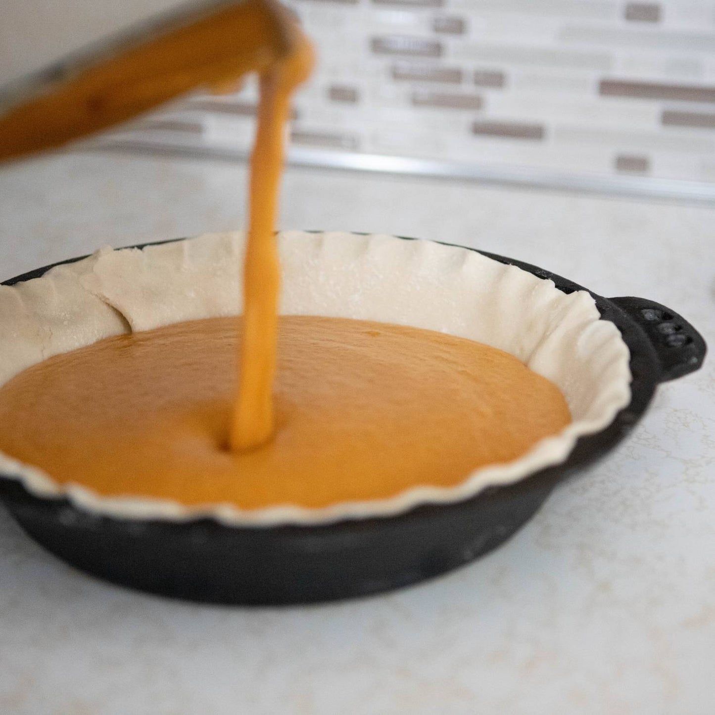 Handcrafted Amish cast iron pie pan with decorative crimped edges being filled with smooth pie filling, ideal for Kitchen & Food, Cookware, Cast Iron, Baking Supplies, Best Sellers, and Promo Eligible collections.
