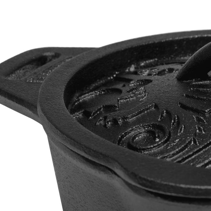 Close-up of a heavy-duty cast iron saucepan lid with raised, embossed self-basting pattern and sturdy handle, crafted for farm, garden, camping, and cookware collections.