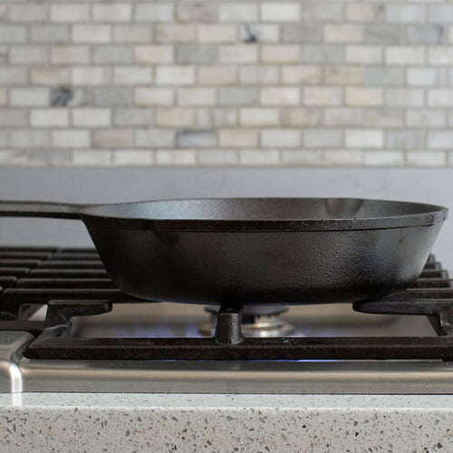 Handcrafted Lodge Classic Cast Iron Skillet resting on a gas stove burner with pre-seasoned surface, known for exceptional heat retention and durability in Kitchen & Food, Cookware, Cast Iron, Best Sellers, Promo Eligible collections.