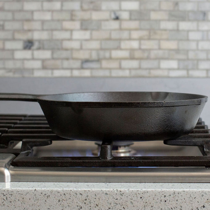 Handcrafted Lodge Classic Cast Iron Skillet resting on a gas stove burner with pre-seasoned surface, known for exceptional heat retention and durability in Kitchen & Food, Cookware, Cast Iron, Best Sellers, Promo Eligible collections.
