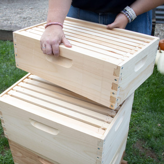 Person assembling a handcrafted natural wood 8-frame beehive box outdoors on grass, showcasing Amish made quality for Farm, Garden & Tool and Beekeeping Supplies collections.