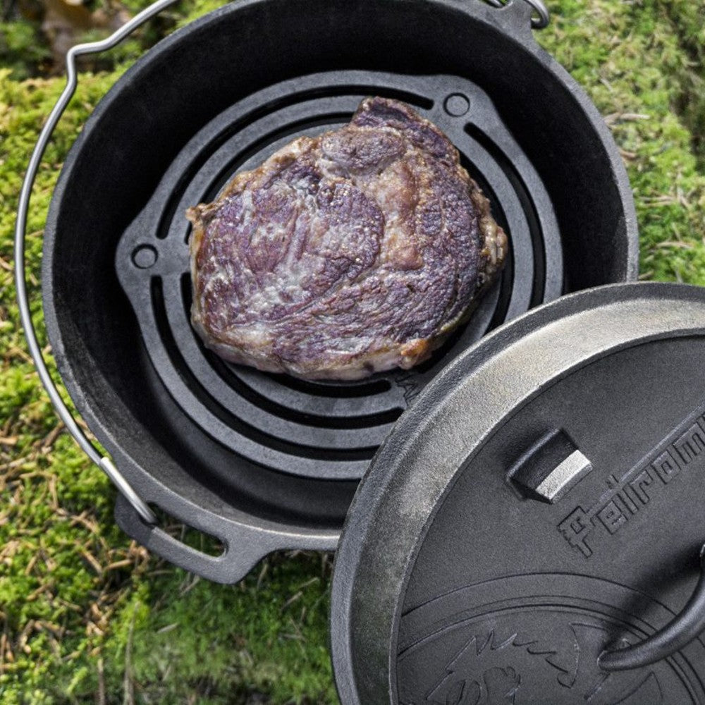 Cast iron stacking grate inside a Dutch oven with a seared steak cooking on top, ideal for even heat distribution during outdoor camping and kitchen use, featured in Farm, Garden & Tool, Kitchen & Food, Camping, Cookware, Cast Iron, Best Sellers, and Promo Eligible collections.