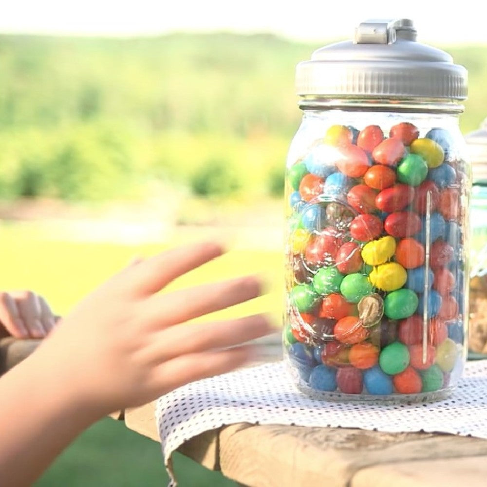 Clear wide-mouth mason jar filled with colorful candy coated chocolates, topped with a durable white pour lid featuring a carry loop, showcased outdoors in bright natural light, ideal for Kitchen & Food and USA Made collections.