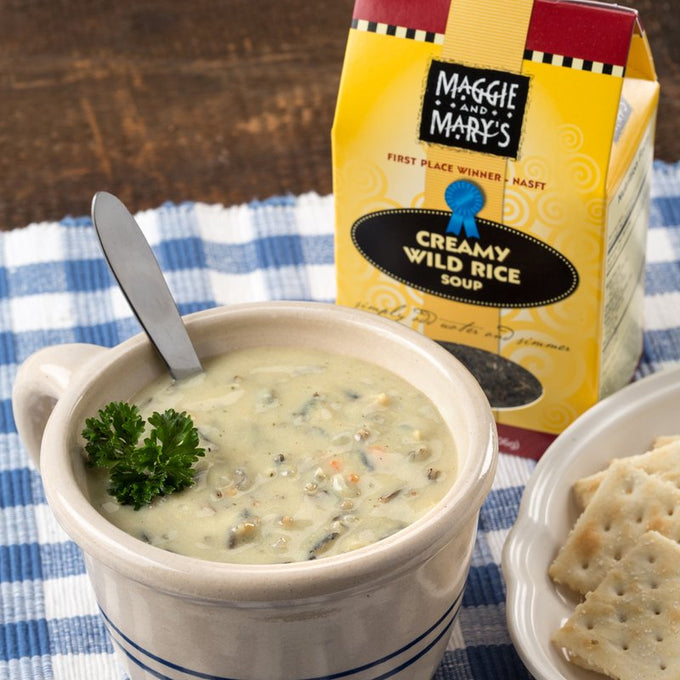 Ceramic bowl filled with creamy wild rice soup garnished with fresh parsley, served with crackers and packaged dry soup mix, ideal for Kitchen & Food, Dry Goods and Mixes, Soups, USA Made, and Best Sellers collections.