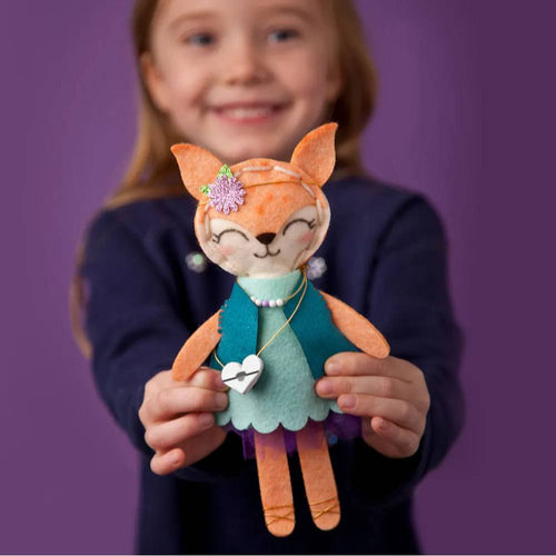 Child holding a handcrafted orange felt fox stuffie dressed in a teal vest, mint green dress, and purple skirt, part of Toys, Books & Games and Children's Toys collections.