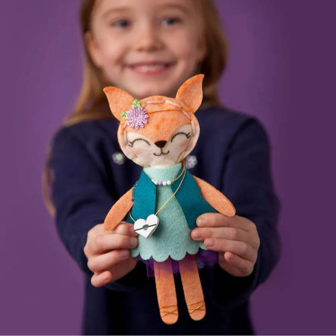 Child holding a handcrafted orange felt fox stuffie dressed in a teal vest, mint green dress, and purple skirt, part of Toys, Books & Games and Children's Toys collections.