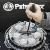 Hand holding a curved metal lid lifter with a coiled handle lifting a hot cast iron Dutch oven lid covered with glowing charcoal briquettes, featured in Farm, Garden & Tool, Camping, Best Sellers, and Promo Eligible collections.