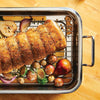 Stainless steel roasting pan with rack holding seasoned roast and roasted vegetables including potatoes, Brussels sprouts, onions, and a pear, part of Kitchen & Food and Cookware collections.