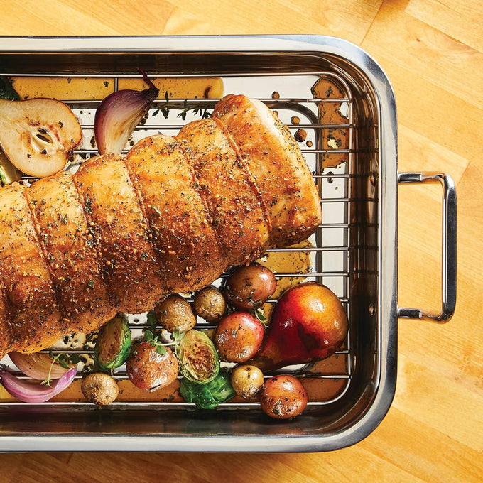 Stainless steel roasting pan with rack holding seasoned roast and roasted vegetables including potatoes, Brussels sprouts, onions, and a pear, part of Kitchen & Food and Cookware collections.