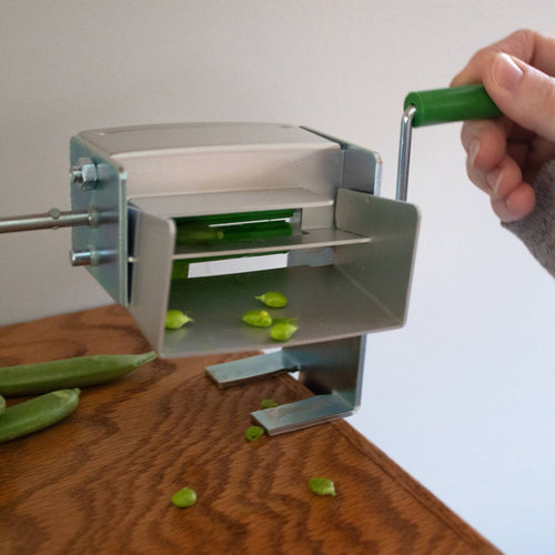 Metal pea sheller with green handle crank clamped to wooden surface, designed for shelling peas or beans in Kitchen & Food, Specialty Equipment, Peelers and Pitters, and USA Made collections.