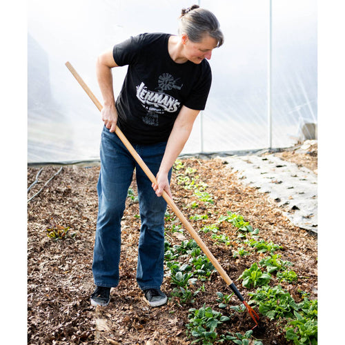 Woman using a handcrafted Amish made garden hoe with a wooden handle and hardened steel blade to cultivate soil in a greenhouse garden, USA made, best seller.