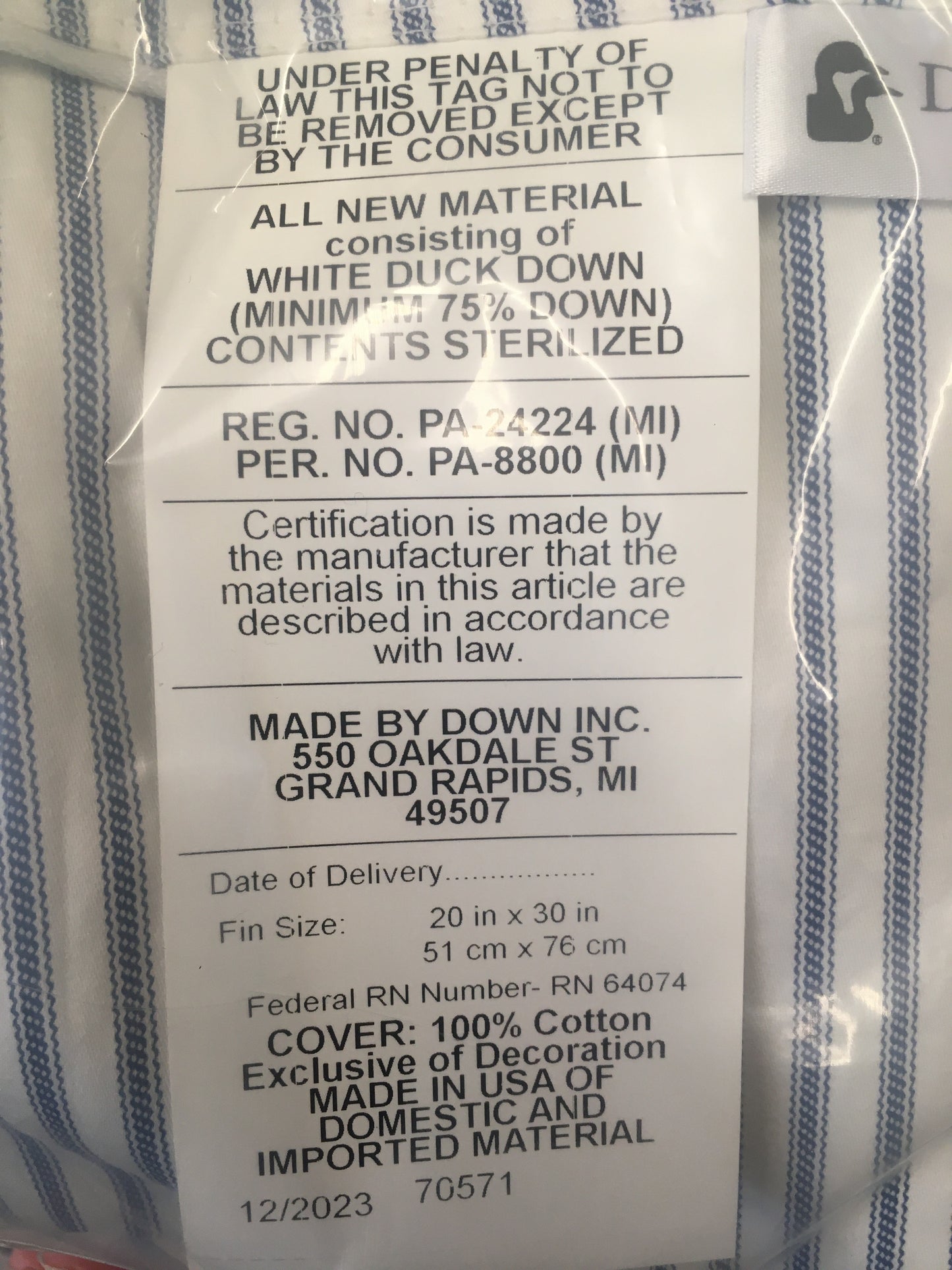 Close-up of a pillow tag detailing white duck down filling with minimum 75% down, sterilized contents, 100% cotton cover, made in USA, fitting Home & Decor, Home Textiles, Best Sellers, and Promo Eligible collections.